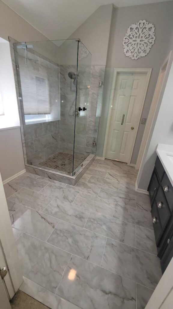 Glass paneled tub-to-shower conversion with new marbled flooring for bathroom remodeling.