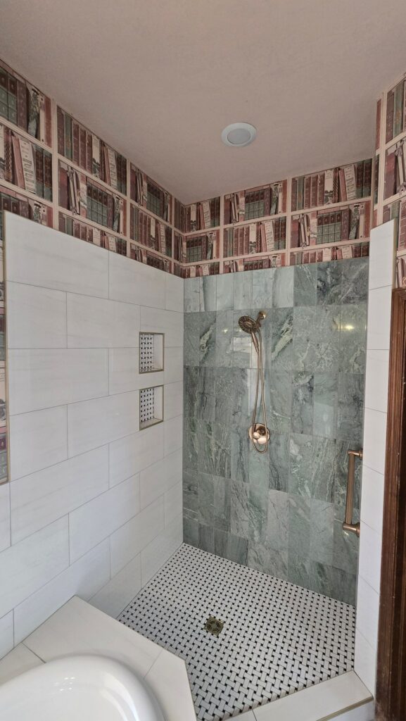 Remodeled Oklahoma City shower with white tile, a green accent wall, mosaic floor, two niches, and a grab bar.