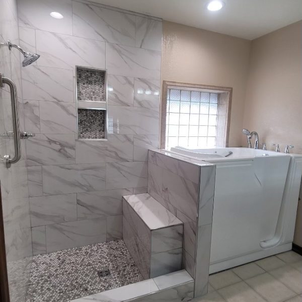 Luxurious tub-to-shower conversion with marbling and a safety handle and seat.